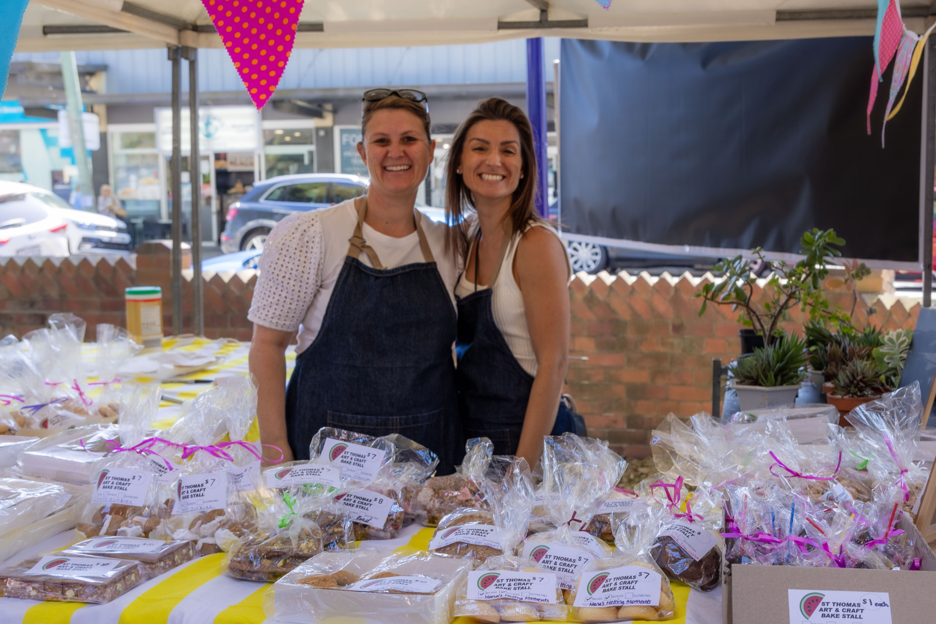 Two smiling volunteers behind the home baked goods stall