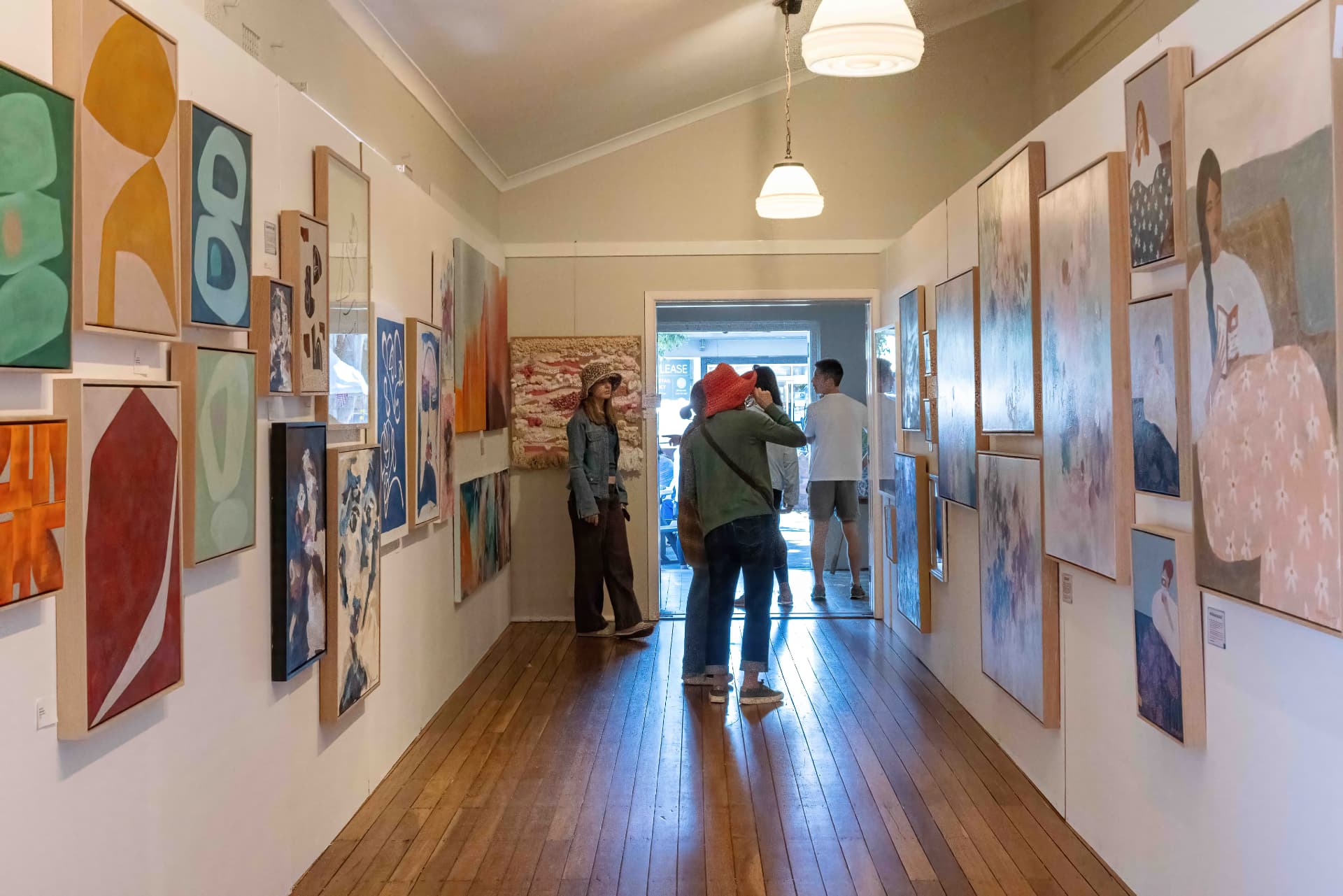 Visitors browsing paintings hung along the gallery hallway at the St Thomas Art & Craft Show