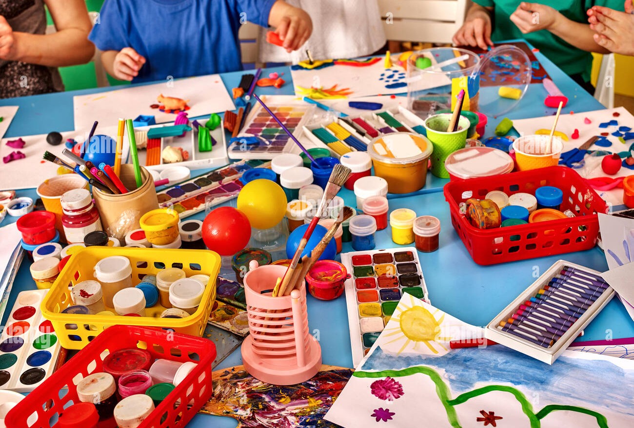 Children painting and crafting at the Kids Craft table with paints, brushes and colourful supplies