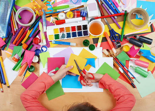 A child cutting coloured paper with scissors at the Kids Craft table