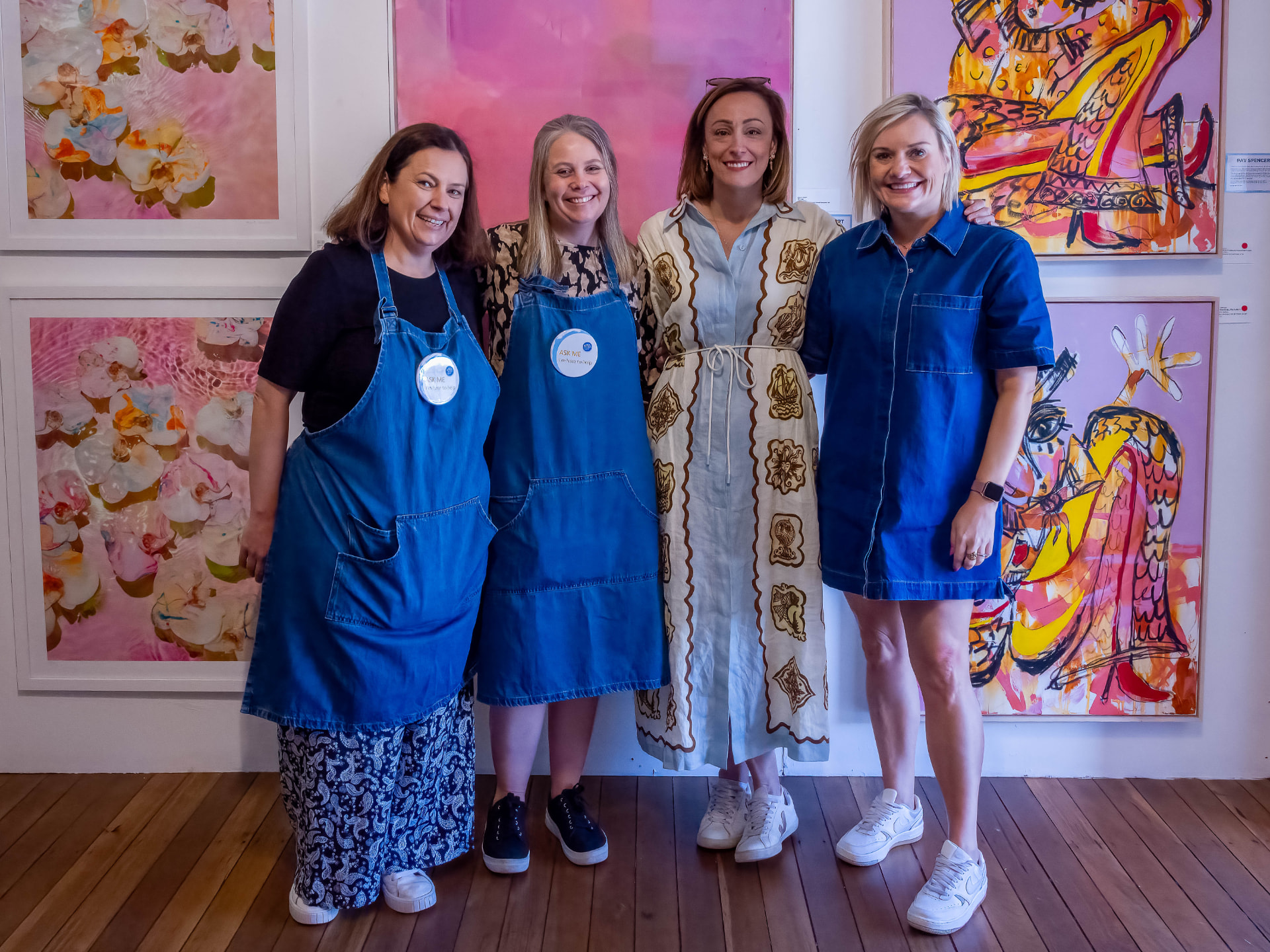 Four smiling gallery volunteers in front of colourful artworks